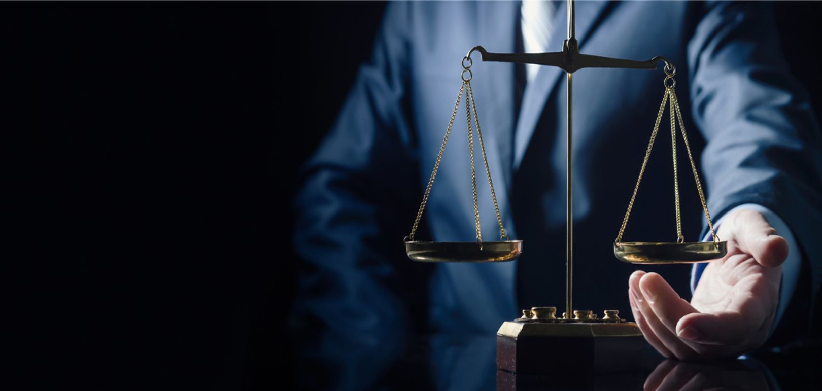 Ein Mann in einem Anzug hält eine Waage der Gerechtigkeit.
